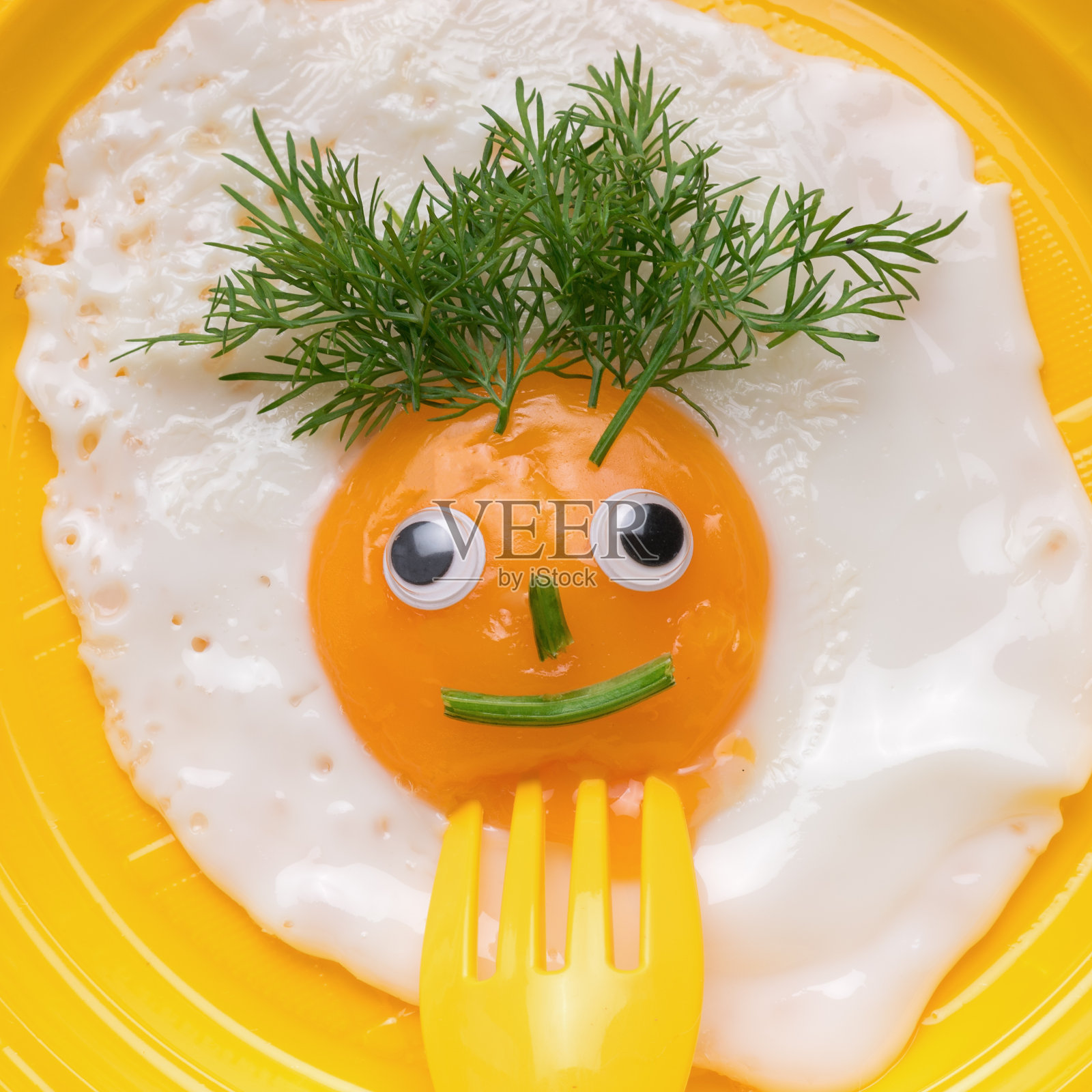 黄色塑料叉子刺穿黄色盘子里的蛋面。最小的概念。一个受欢迎的早餐。照片摄影图片