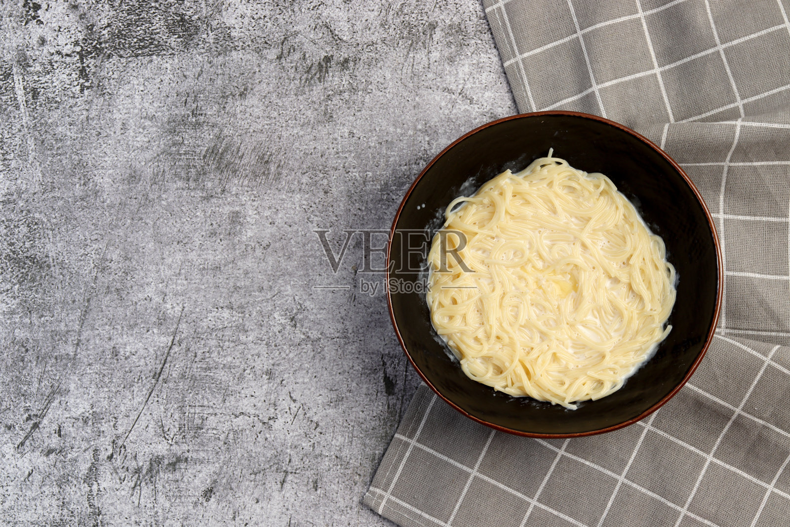 在深灰色的背景上，碗里有牛奶面条汤。俯视图，平面布局照片摄影图片