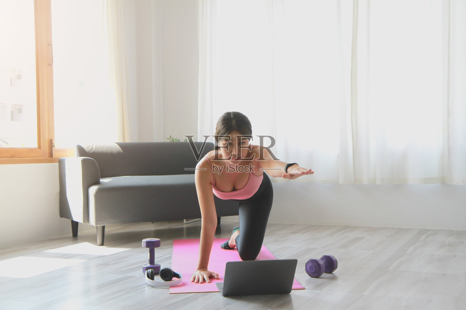 下班后女子在家通过在线课程练习瑜伽。缓解压力、放松肌肉、呼吸练习、锻炼、冥想。照片摄影图片