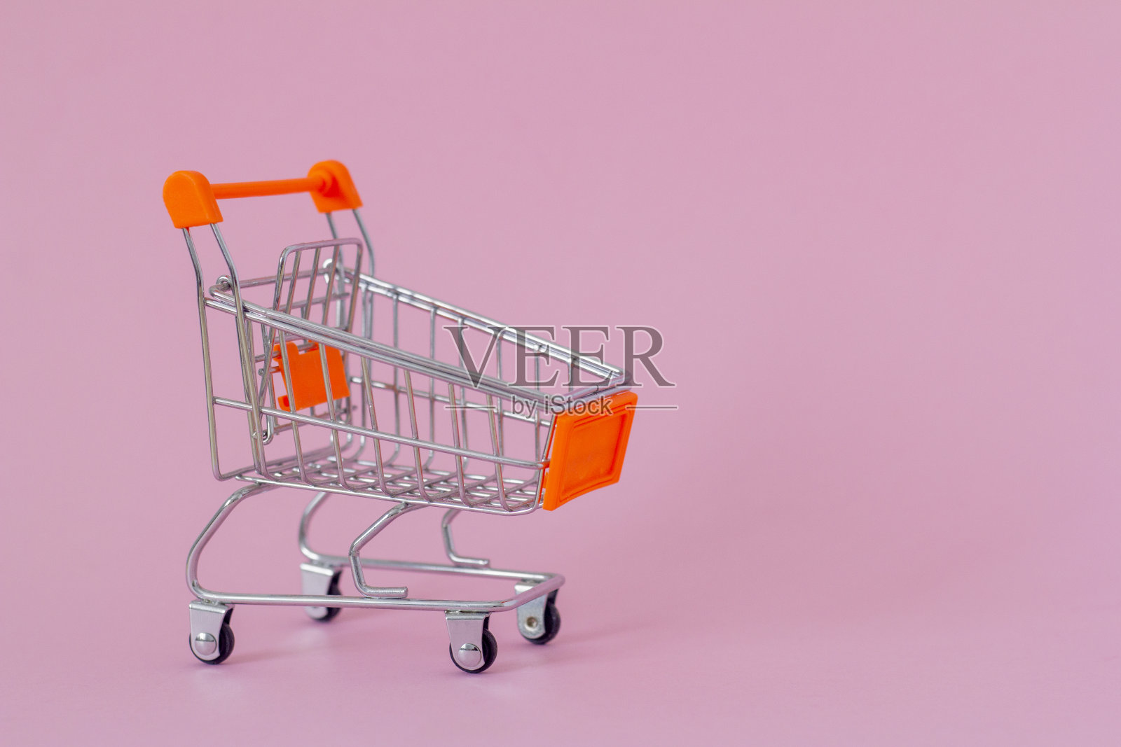 购物车在粉红色的背景与拷贝空间。照片摄影图片