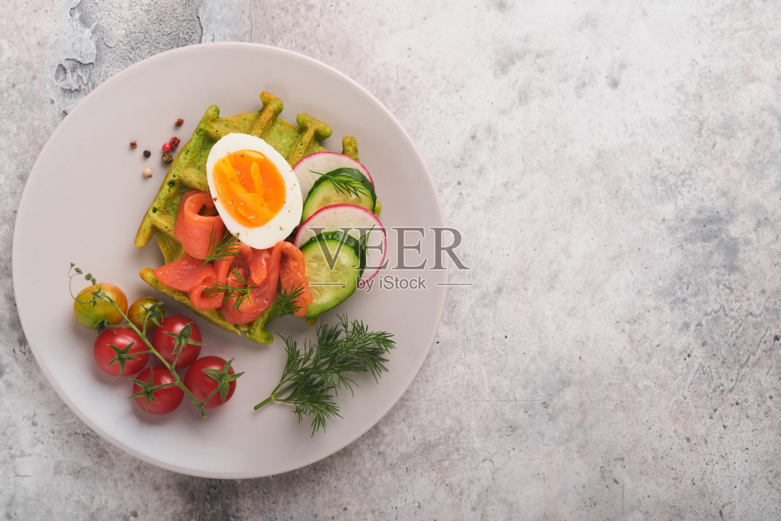 美味的华夫饼。早餐绿色华夫饼，野蒜或菠菜，鸡蛋，西红柿，三文鱼，放在灰色的混凝土桌子上。清淡的晚餐、午餐或早餐。前视图。模拟。照片摄影图片