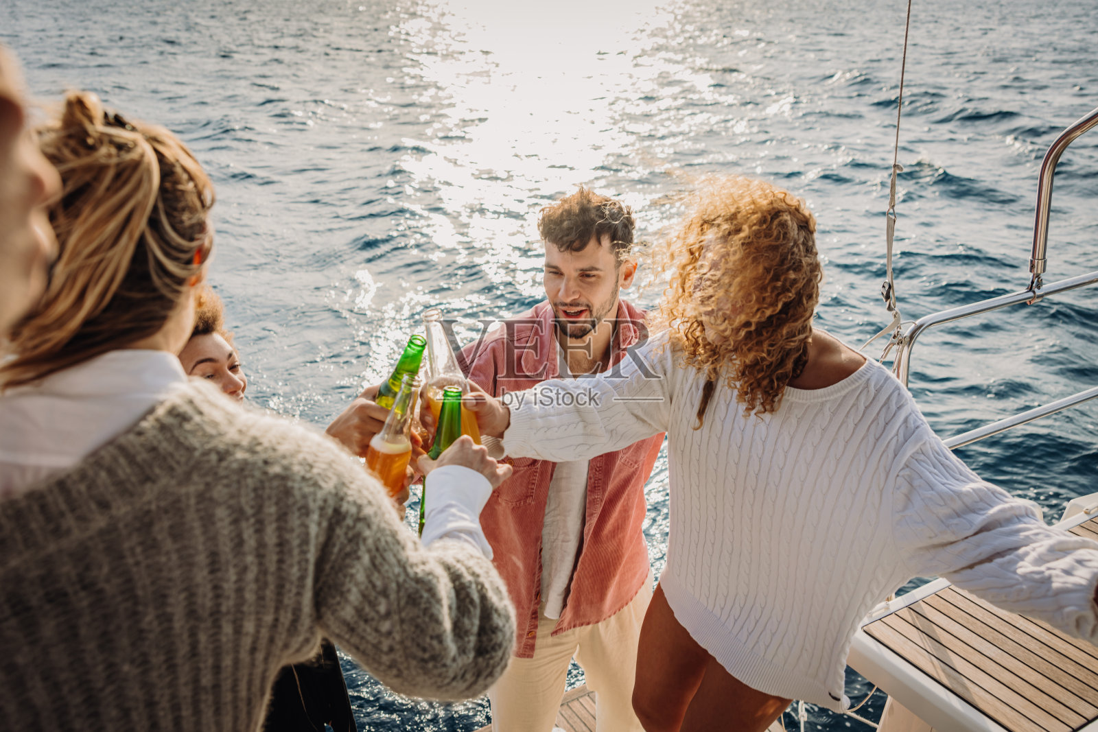 晚上，三个女人和一个男人站在帆船的甲板上，在船上聚会上一起举杯庆祝照片摄影图片