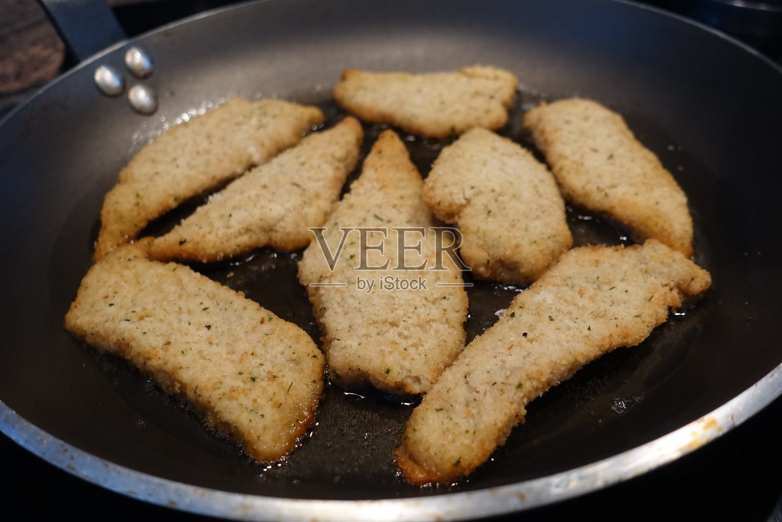 裹面包屑的柠檬鱼片在平底锅里煎照片摄影图片