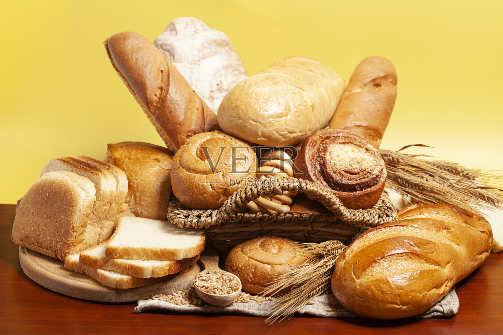 面包上有小圆面包，干面包圈，黄色底色的麦穗。烹饪的背景照片摄影图片