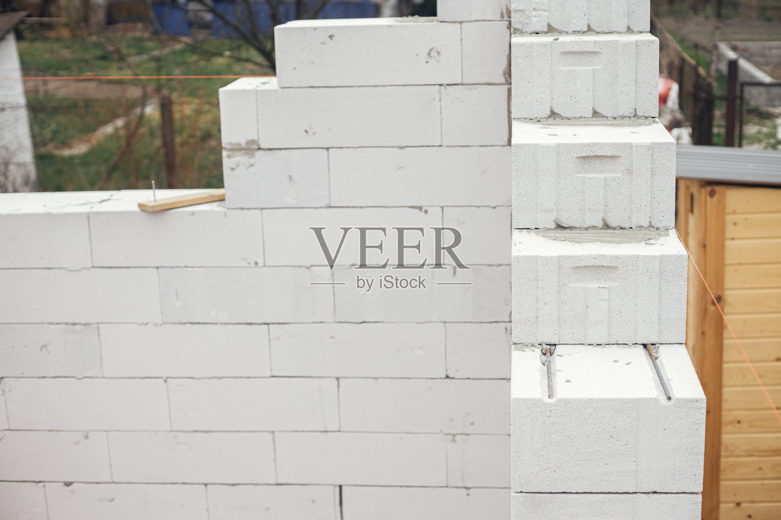 铺设带钢筋和粘合剂的蒸压加气混凝土砌块。安装白色方块关闭。砌筑。施工现场房屋建造过程照片摄影图片