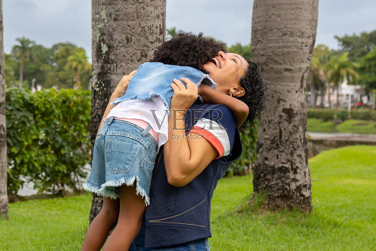 一个留着爆炸头的小女孩和她妈妈在公园里玩的肖像照片摄影图片