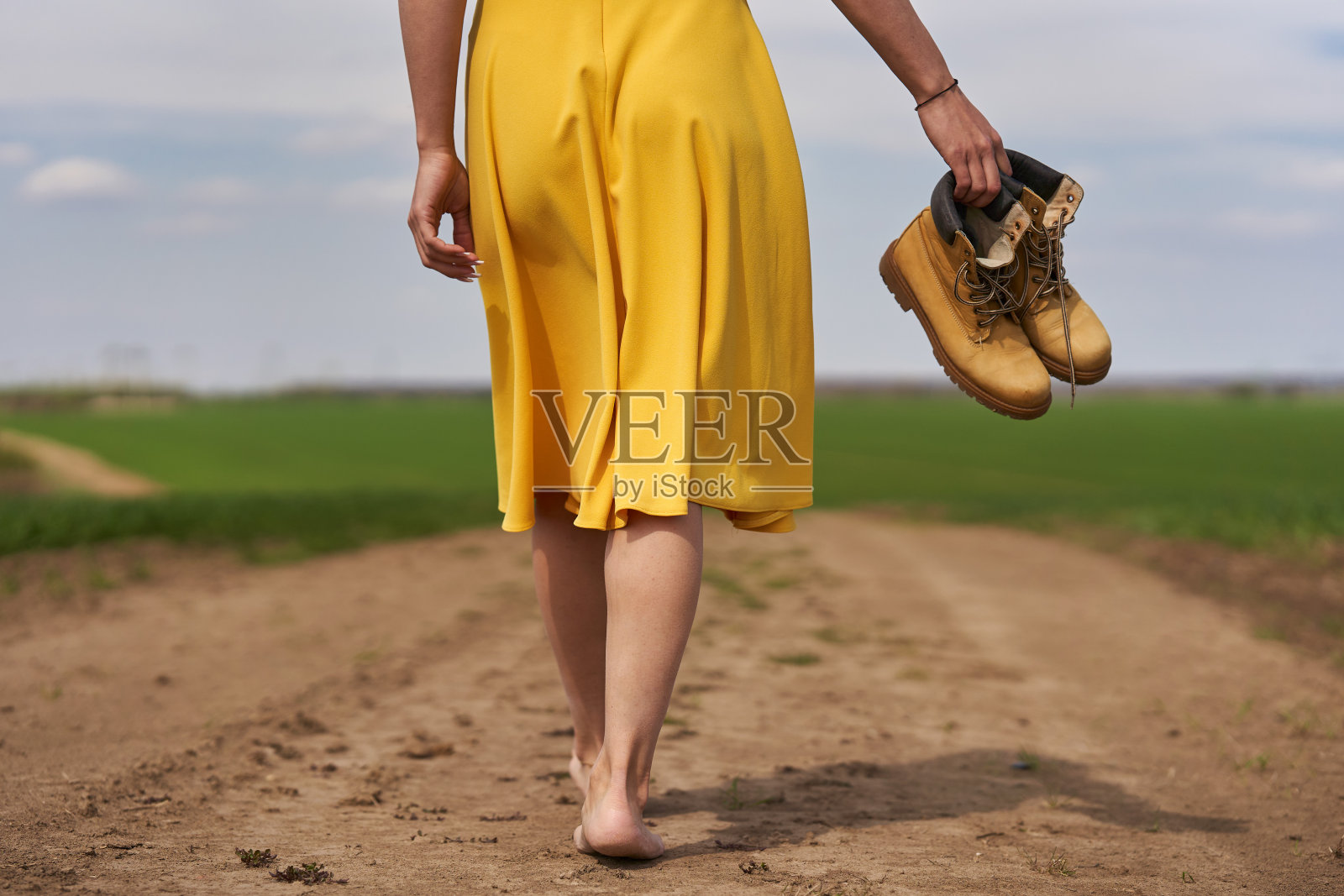 一个年轻女人赤脚走在土路上照片摄影图片