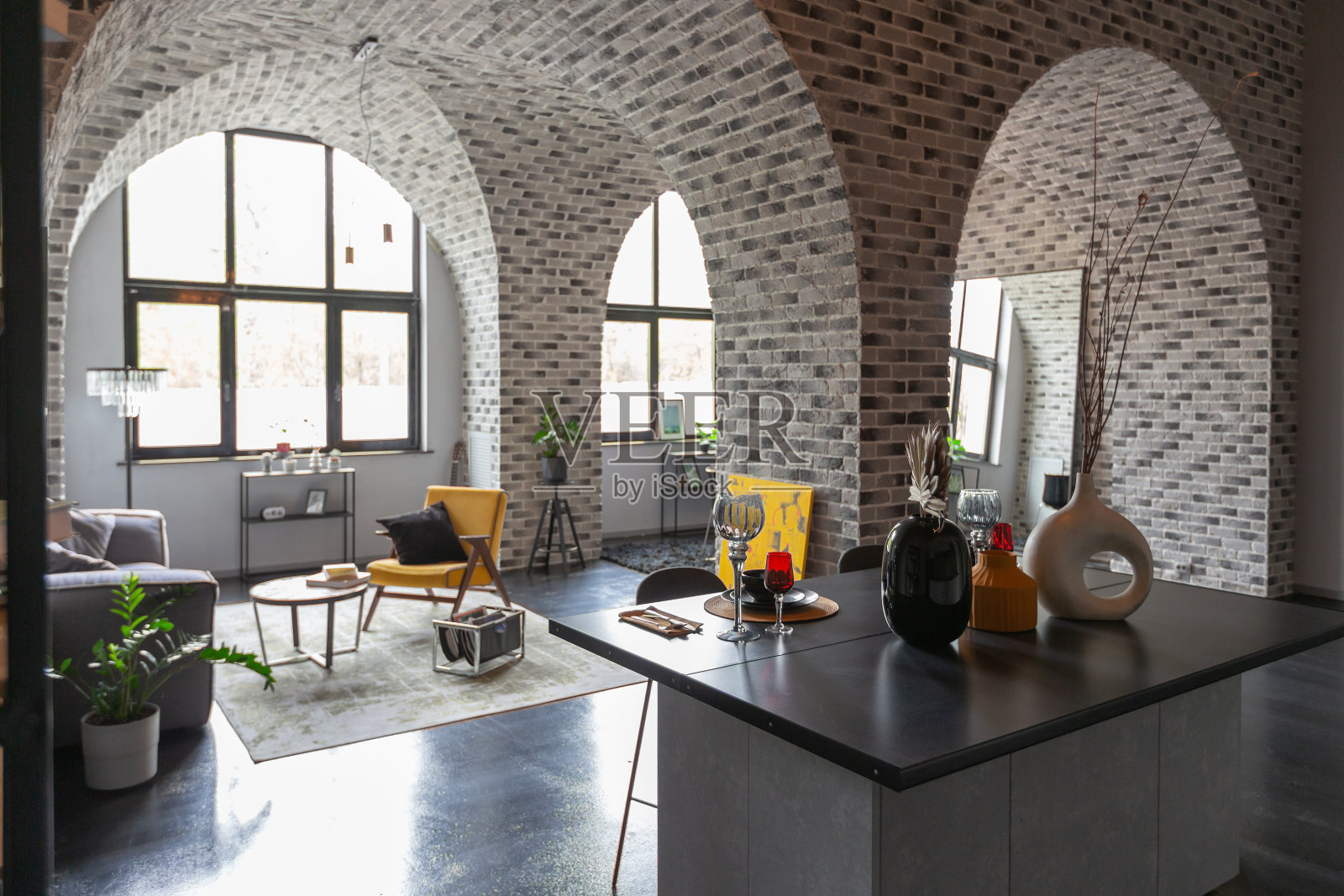 现代豪华设计的残酷公寓内部与拱门风格的中世纪城堡明亮的口音。一个时尚的灰色厨房区域，带有一个岛，用于烹饪或消磨时间照片摄影图片