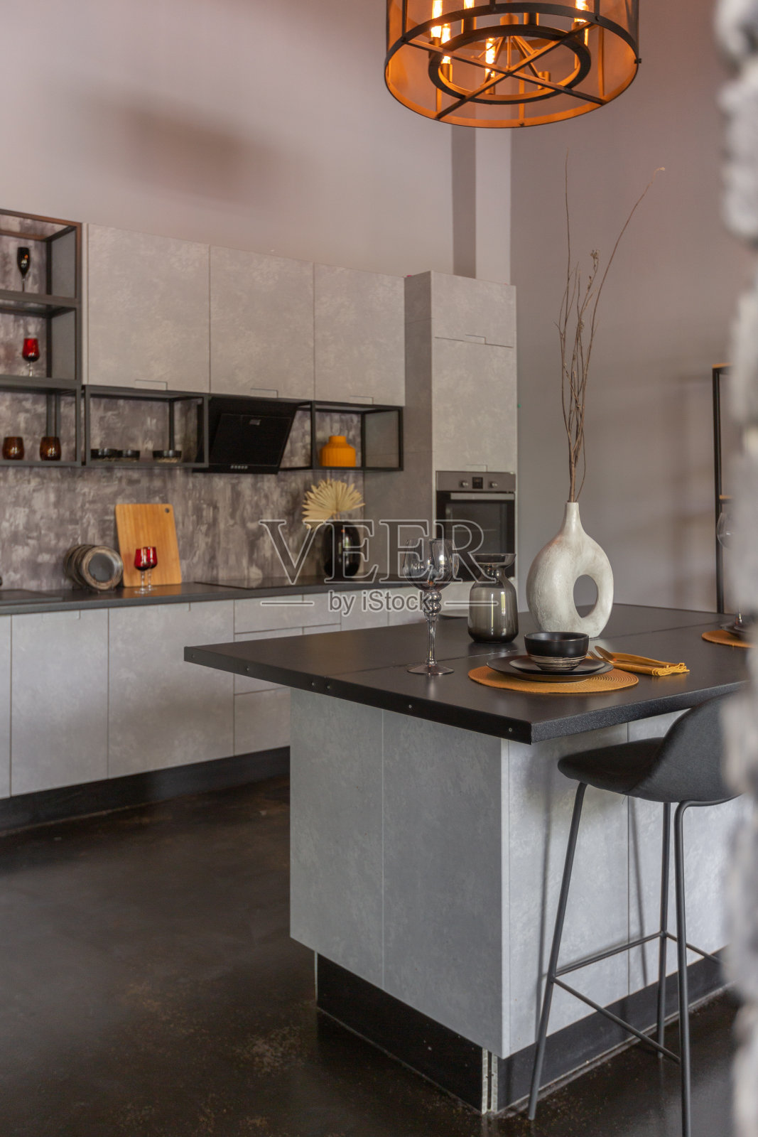现代豪华设计的残酷公寓内部与拱门风格的中世纪城堡明亮的口音。一个时尚的灰色厨房区域，带有一个岛，用于烹饪或消磨时间照片摄影图片