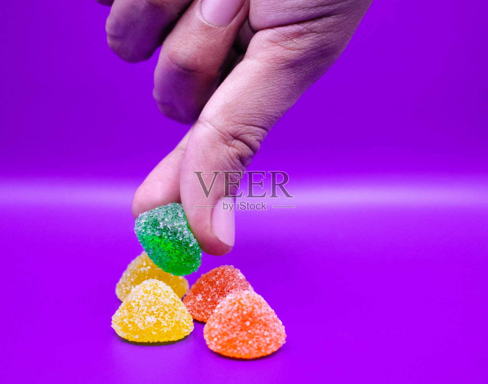 凝胶被一只手拿在紫色的背景上照片摄影图片