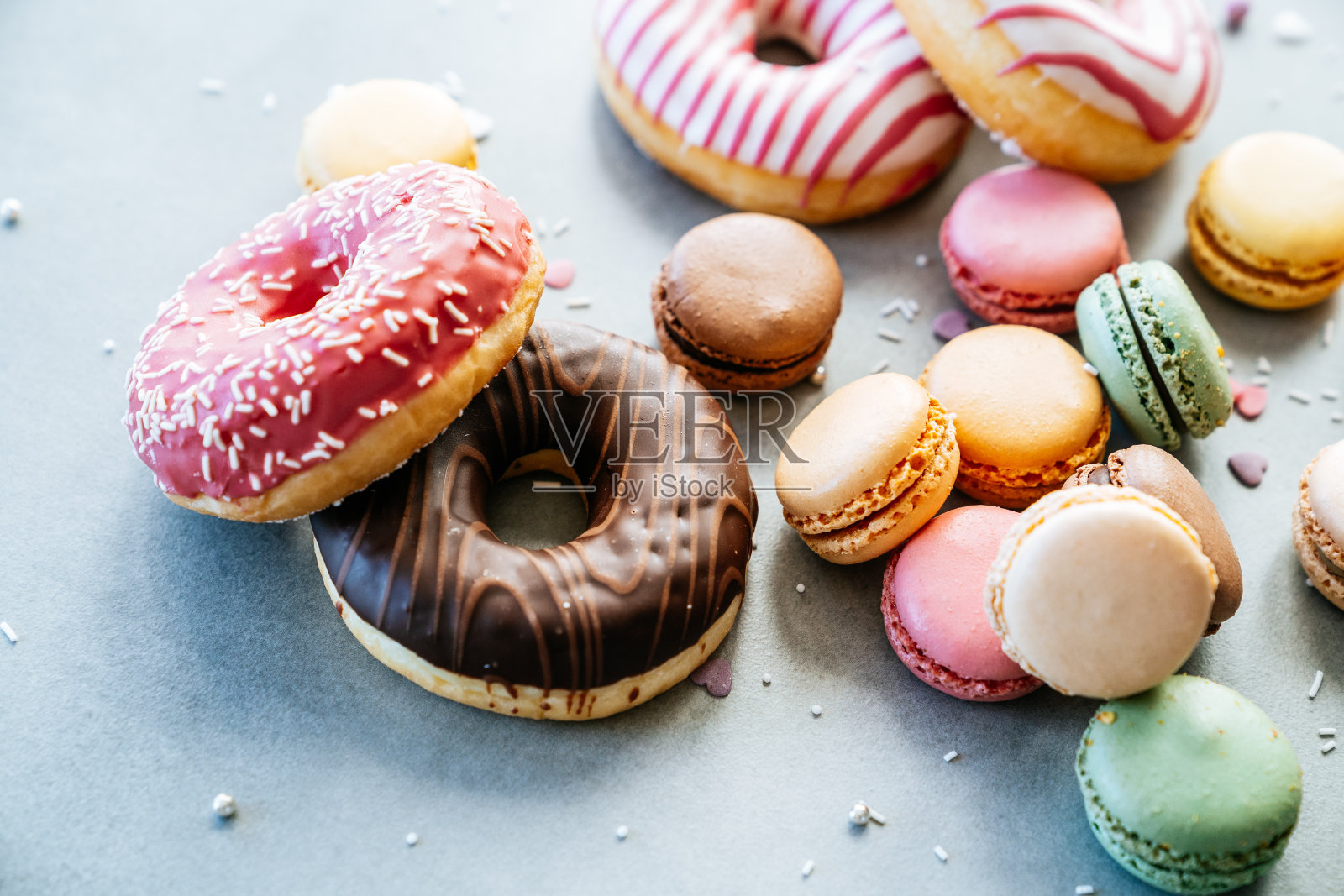 混凝土背景上五颜六色的马卡龙和甜甜圈。照片摄影图片