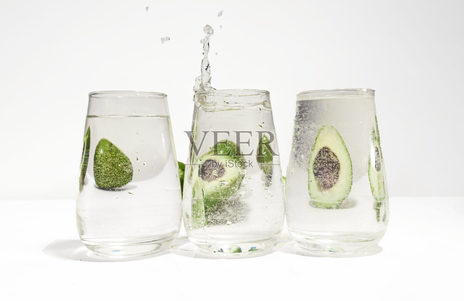 鳄梨通过液体和装满水的玻璃器皿变形。通过水的光学畸变。健康食品的概念照片摄影图片