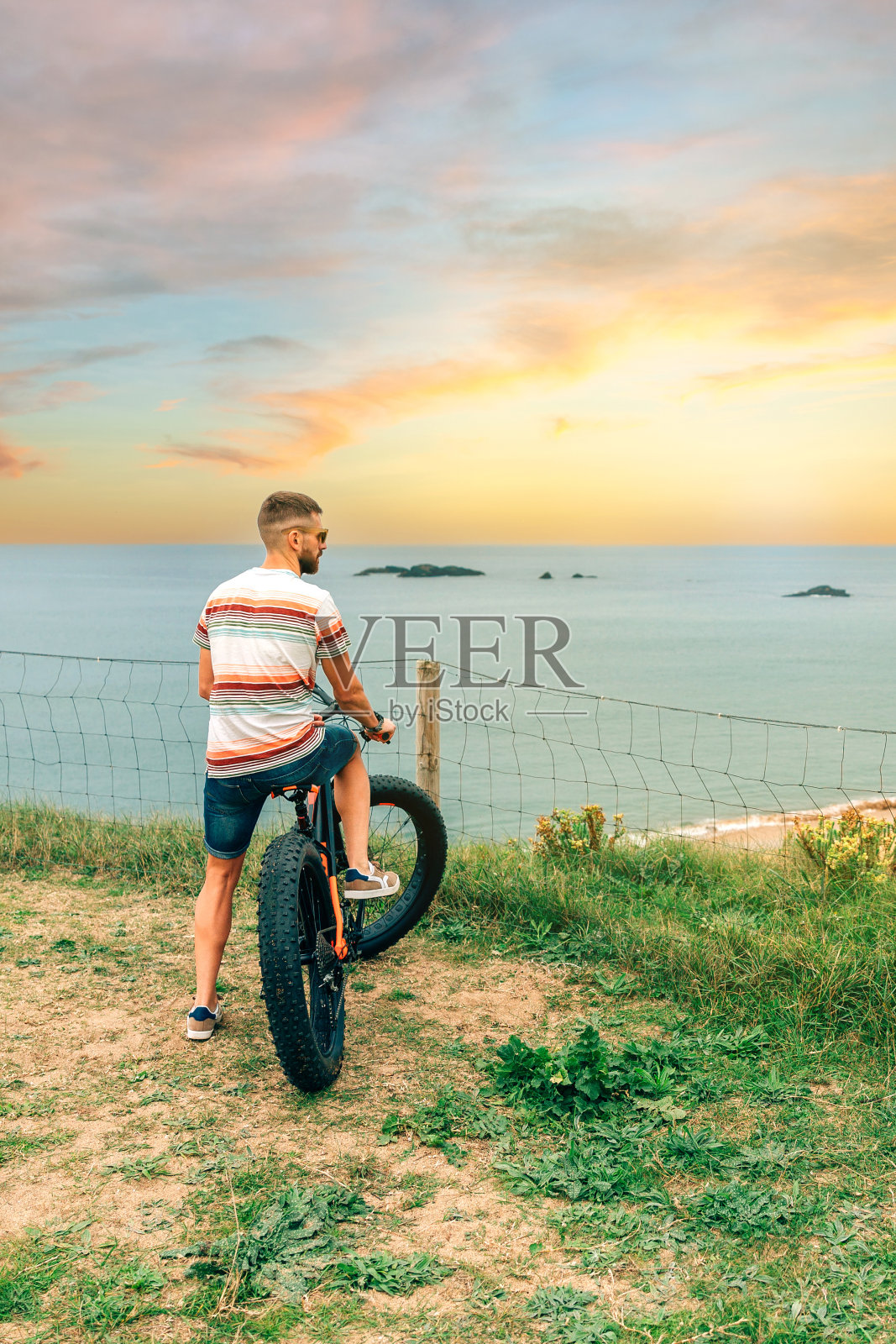 一个男人骑着一辆肥大的自行车，从海边望着大海照片摄影图片