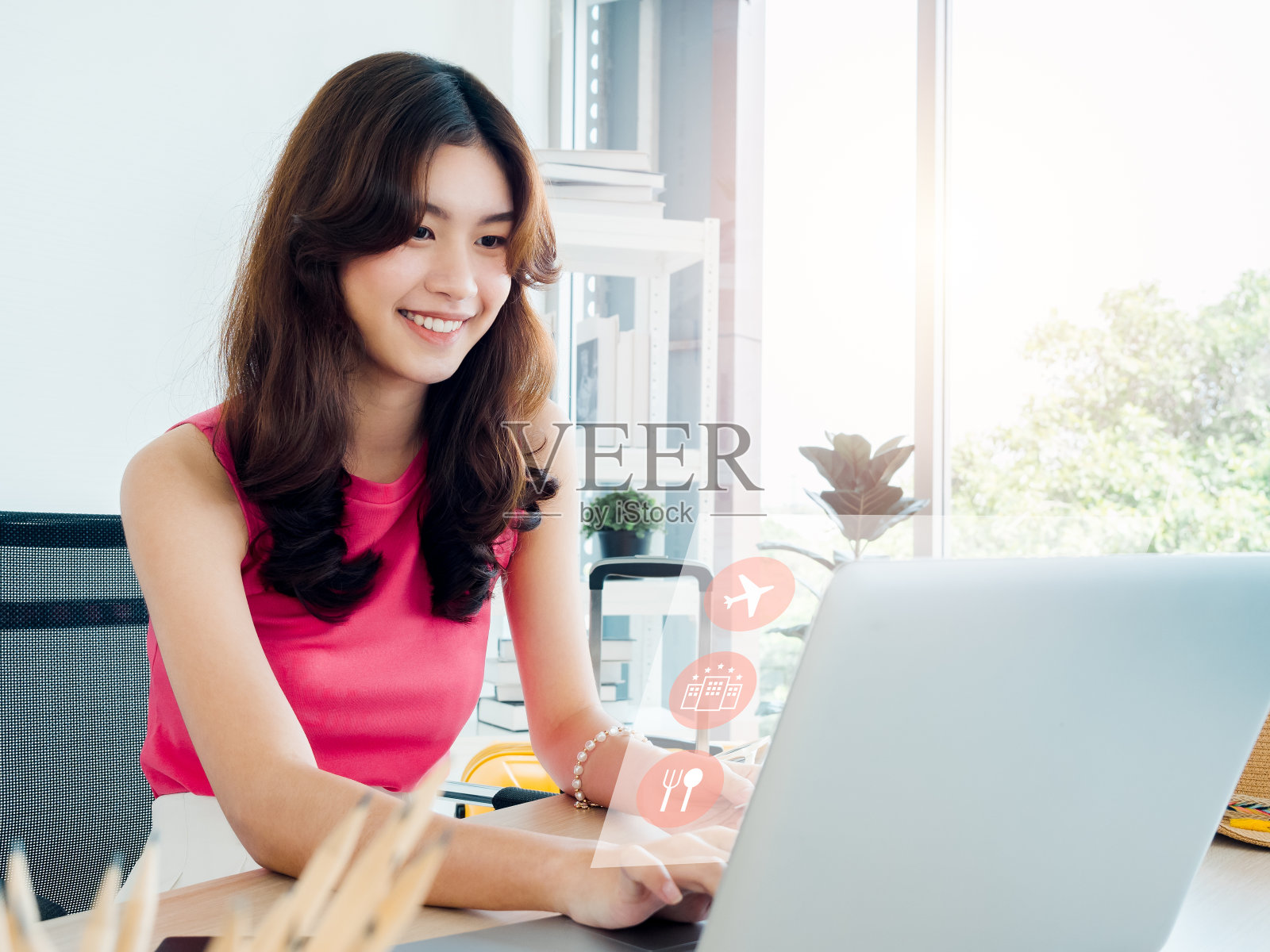 旅行和度假计划概念：快乐的年轻亚裔女性在家中使用笔记本电脑搜索旅行信息，包括航班预订、酒店和餐厅照片摄影图片