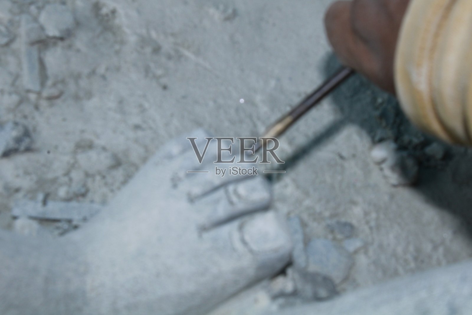 工匠手雕刻石头的特写，手握凿子，手动锤击。照片摄影图片