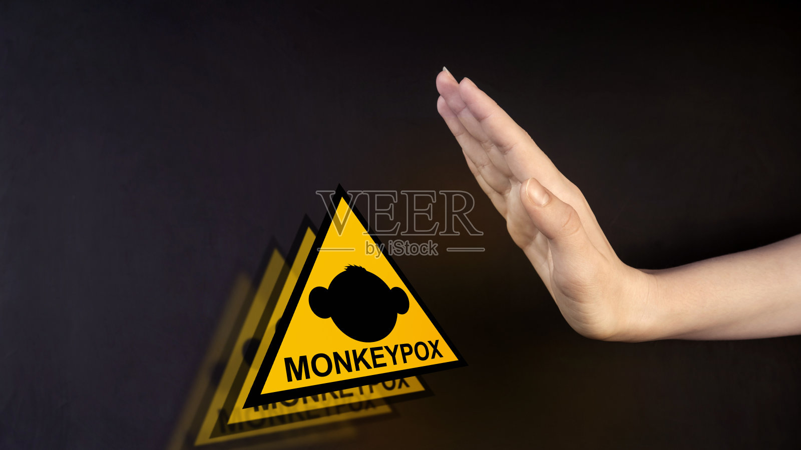 猴痘。猴子停车标志。病毒流行疾病。这只手指向一个标志。黑色背景。照片摄影图片