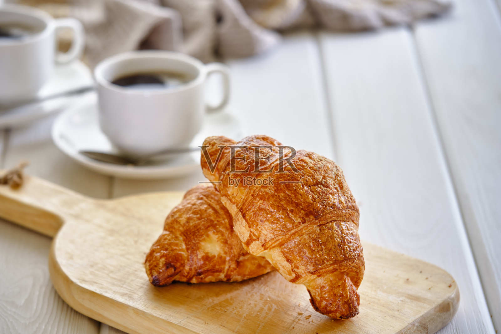 脆脆的杏仁羊角面包和热黑咖啡放在木板上，放在轻混凝土桌子上。照片摄影图片