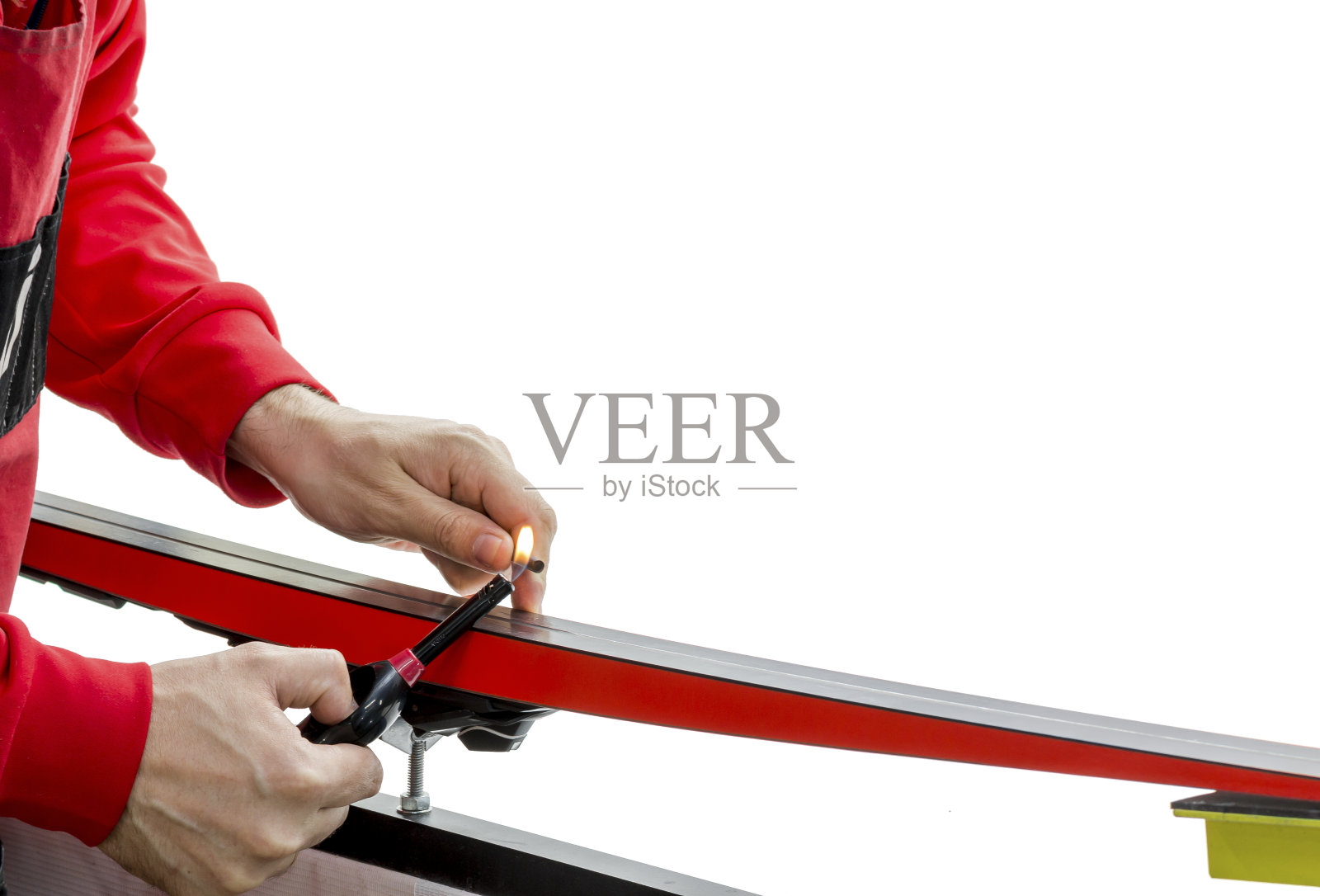 一名军人用打火机融化修复塑料，用于白色背景上滑雪滑面的划痕照片摄影图片