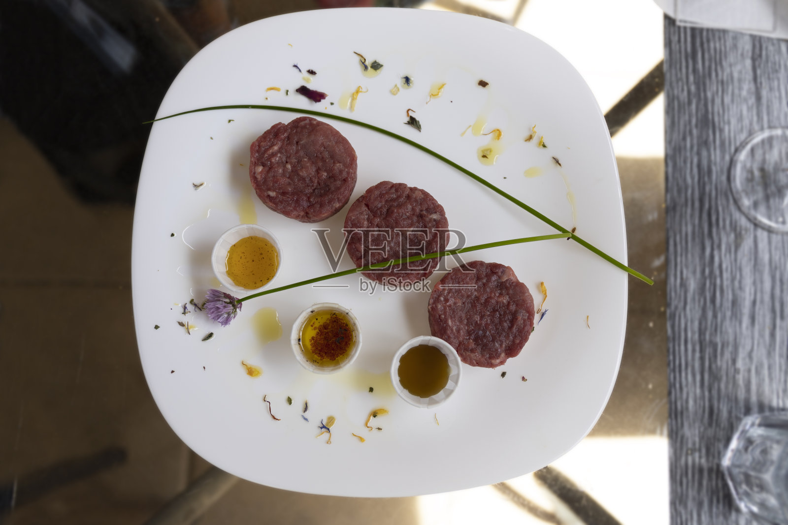 白色盘子里的鞑靼牛肉配上酱汁。生肉。照片摄影图片