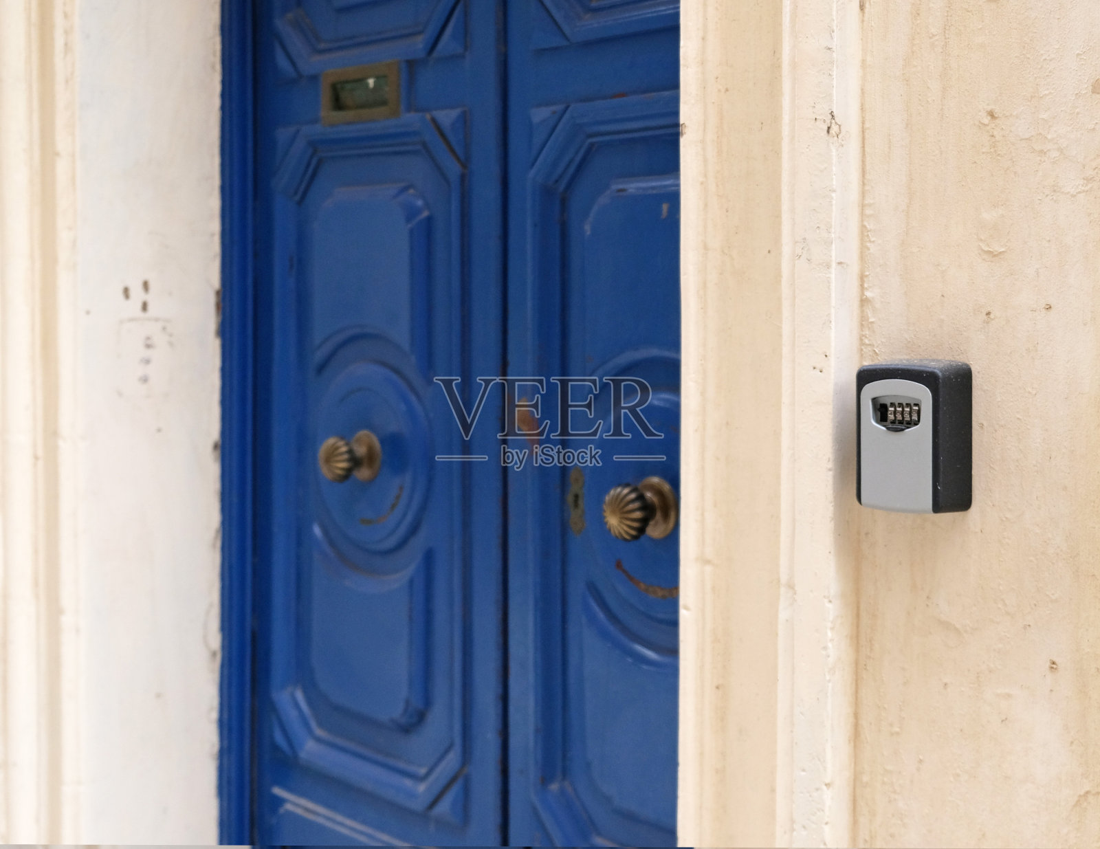 智能钥匙锁安装在墙上，用于出租公寓。当客人到达旅游公寓，主人无法打开房门时使用保险箱。安全进入生活空间。蓝色的门照片摄影图片