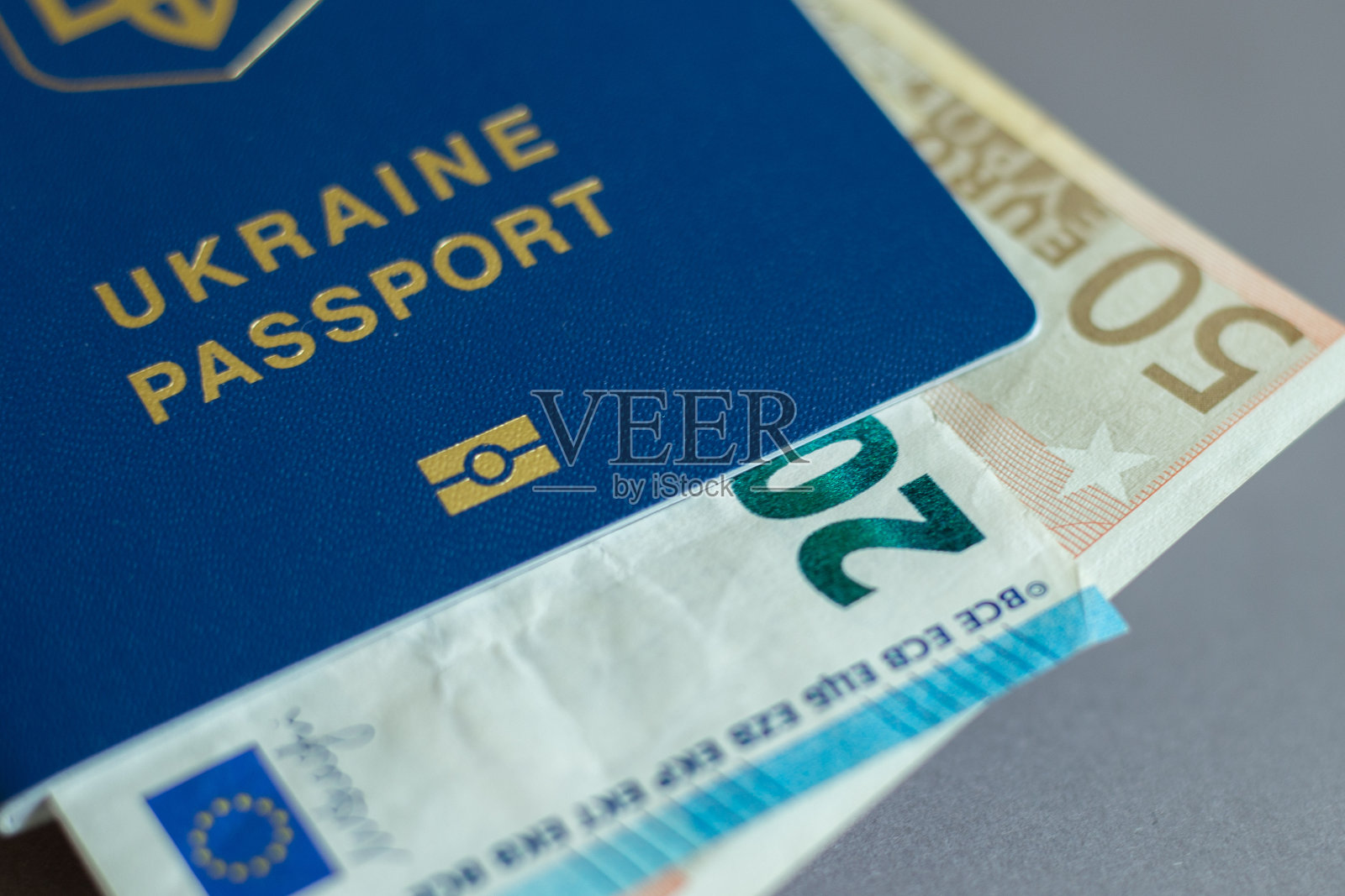 戴着白色医疗手套的女性手拿着蓝色封面的乌克兰护照，黑色背景是一张欧元钞票，冠状病毒、流行病、旅行禁令的概念照片摄影图片