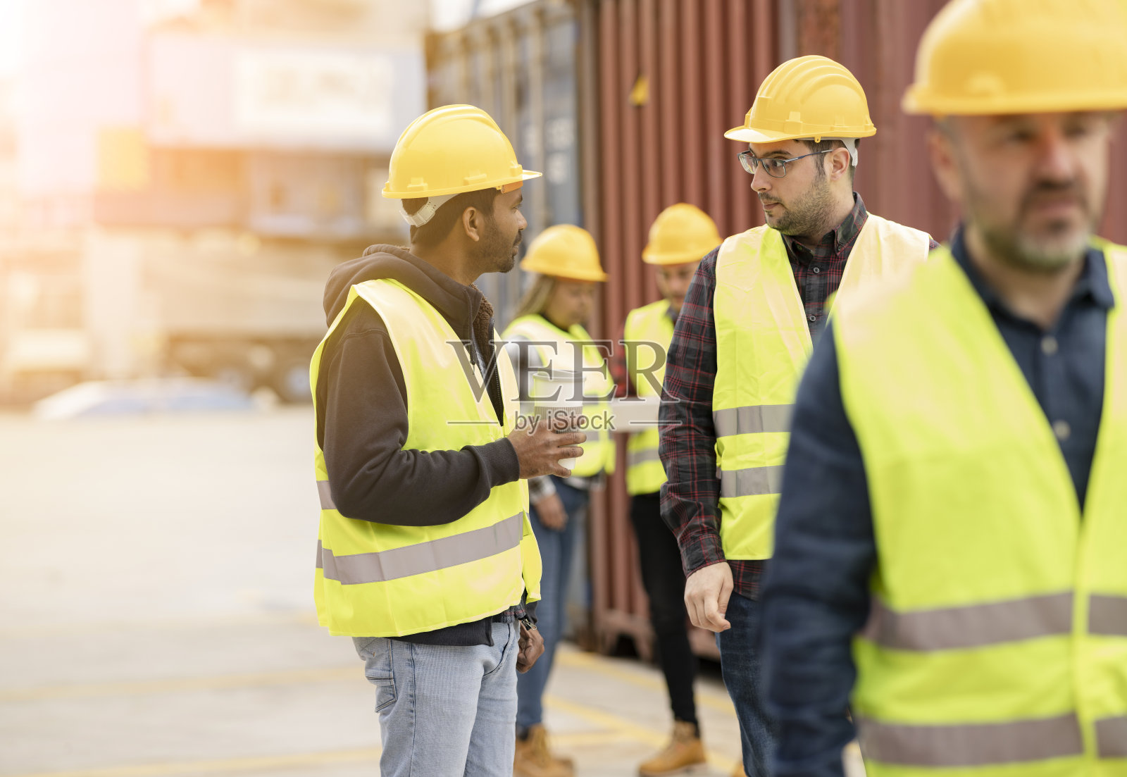 一群物流工人在集装箱、港口附近讨论航运商品。工作-关注印度人-照片摄影图片