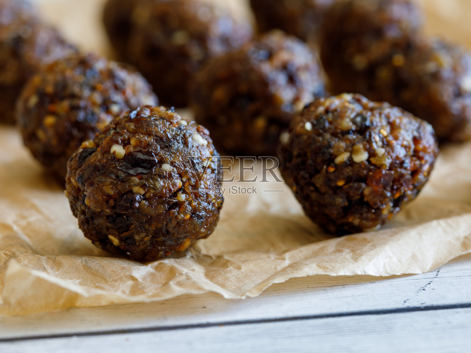 自制美味能量球:用葡萄干、西梅、枣、核桃、无花果做成的巧克力球蛋糕，放在烤纸上照片摄影图片