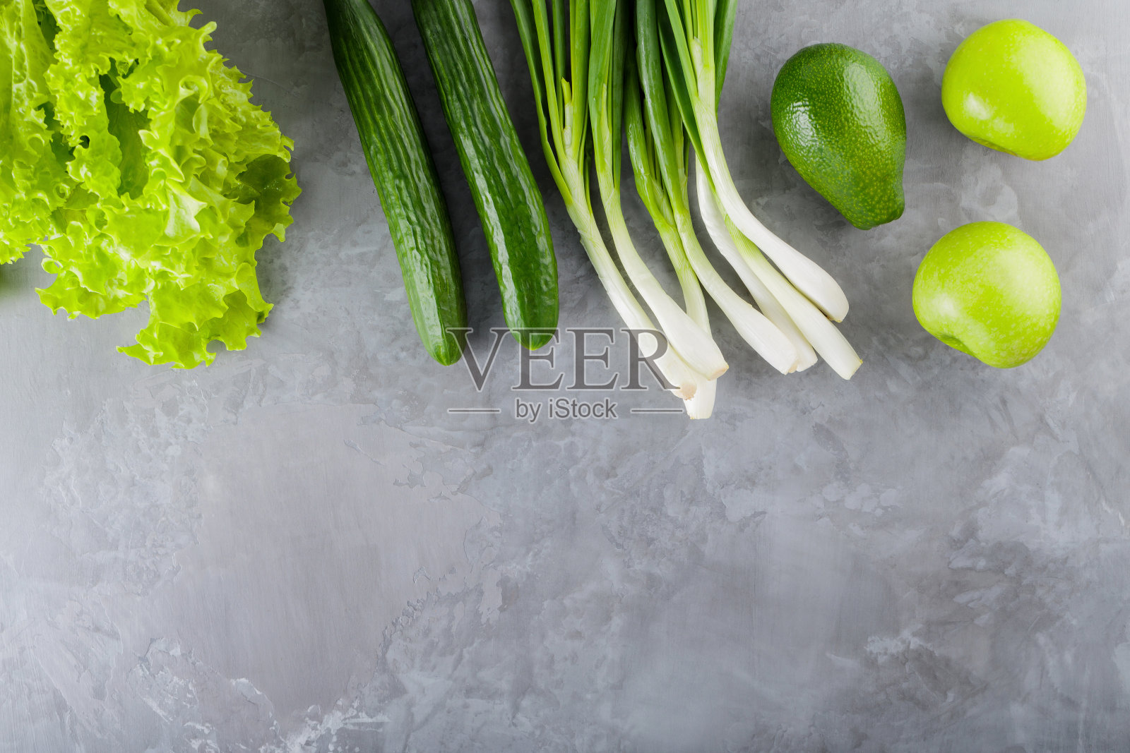 绿色健康蔬菜配灰色混凝土。新鲜蔬菜和水果:生菜，黄瓜，大葱，牛油果，青苹果。健康减肥食品理念。前视图。本空间照片摄影图片