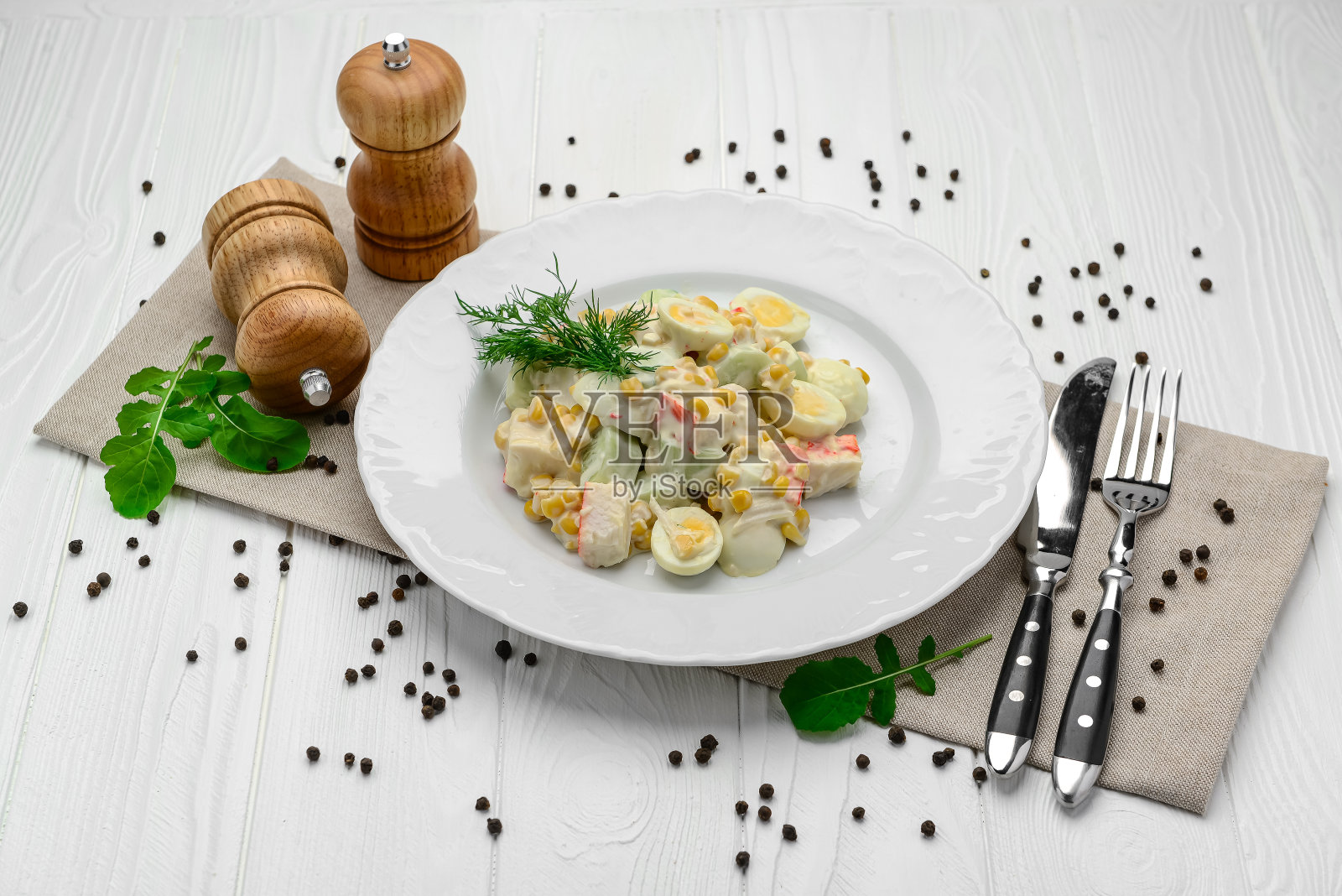 清淡的餐桌上有蟹肉条、甜玉米、黄瓜、鸡蛋和蛋黄酱。照片摄影图片