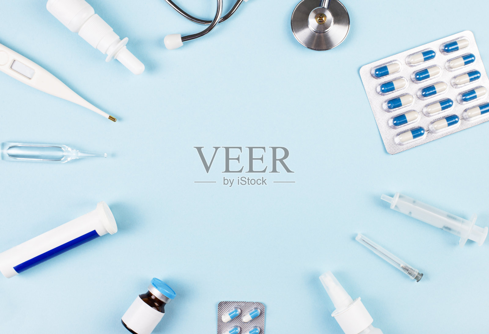 浅蓝色背景描绘了听诊器、温度计、药丸和药瓶，里面有插入文字的地方。从以上观点。医学的概念照片摄影图片