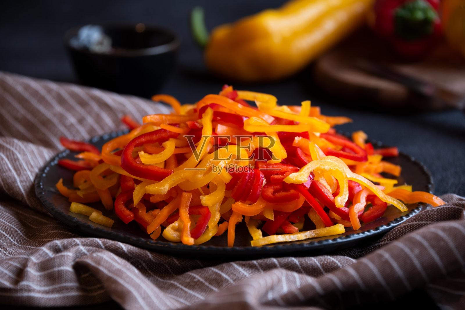 五颜六色的切椒放在黑色的碗里照片摄影图片