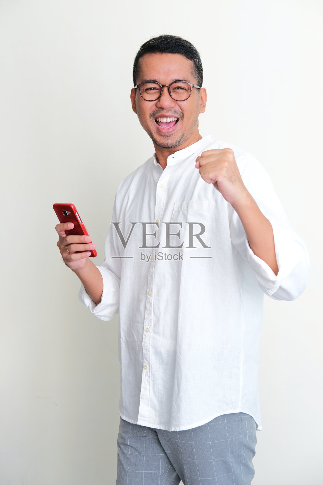 一名亚洲成年男子手持手机，表情热烈地看着镜头照片摄影图片