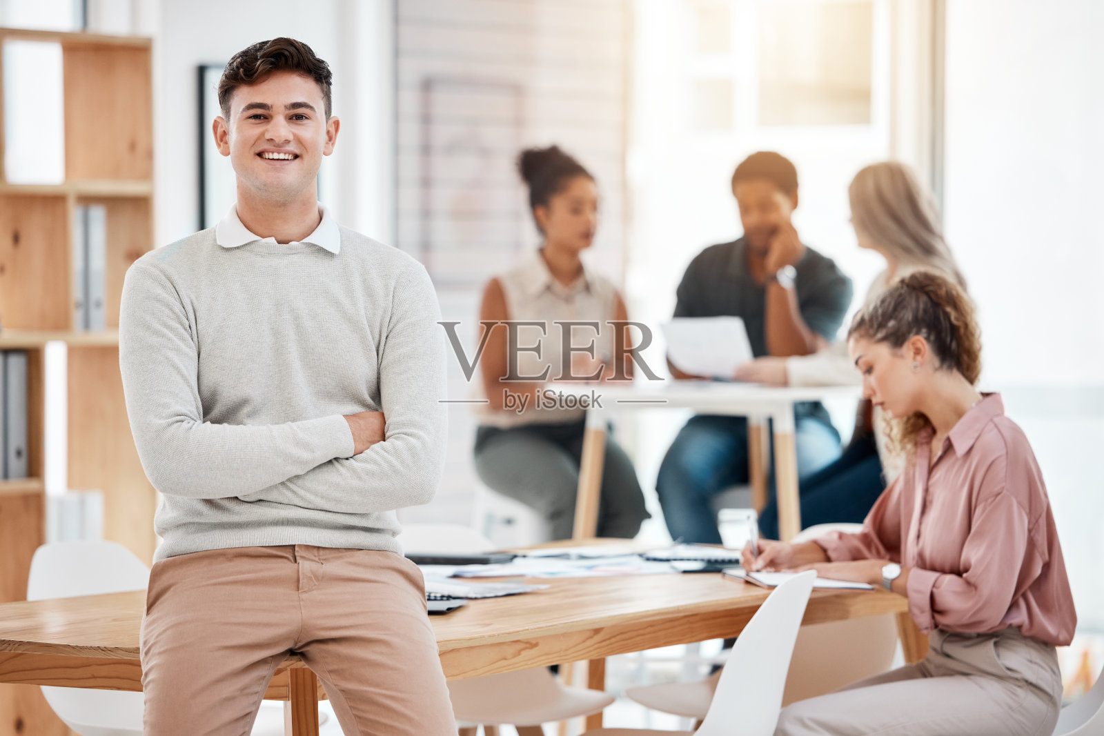 一位欢快的白人商人双臂交叉站在办公室里的肖像。一个自信的男经理的头像，微笑着站在工作中照片摄影图片