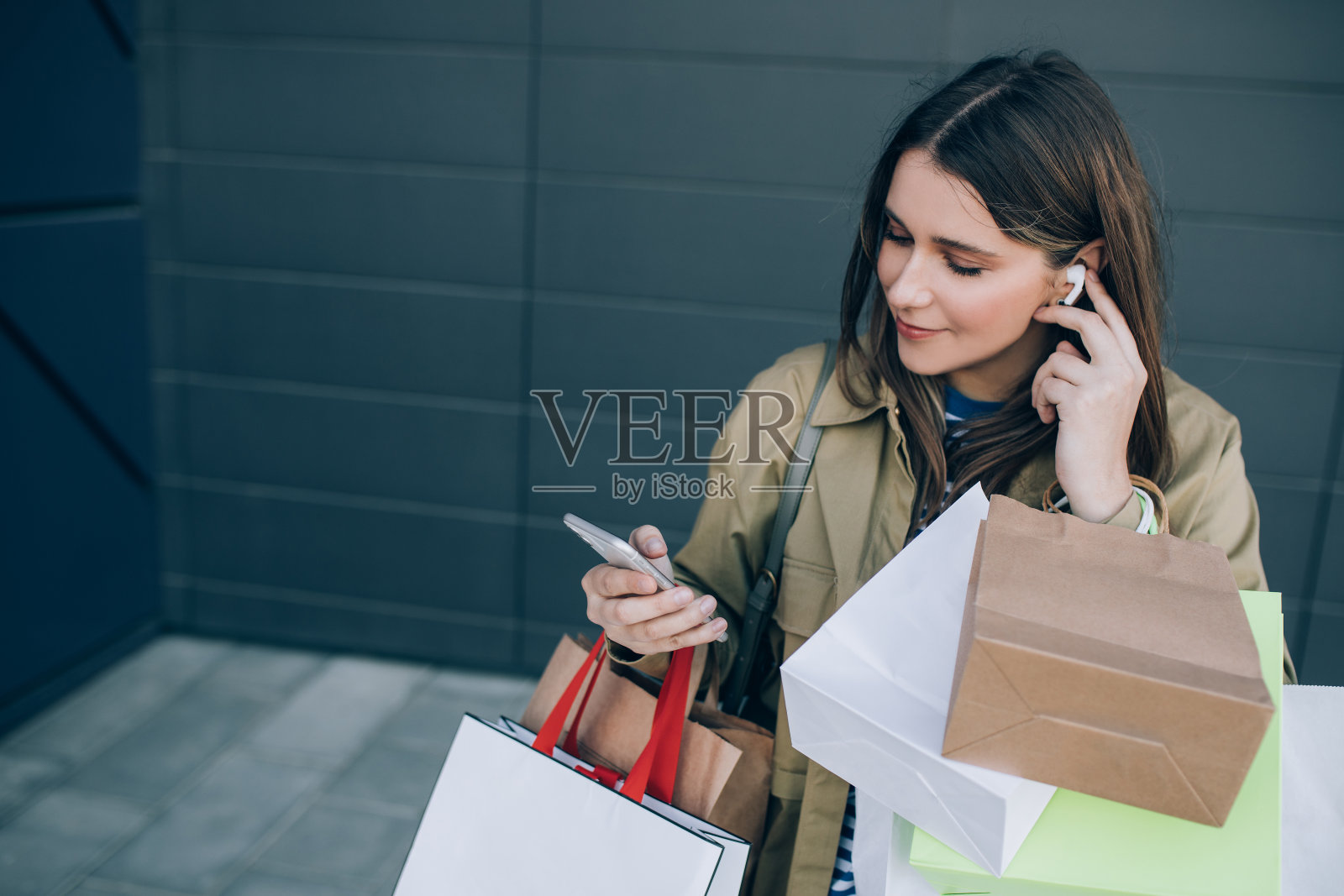 快乐美丽的女人拿着包享受购物，使用智能手机。照片摄影图片