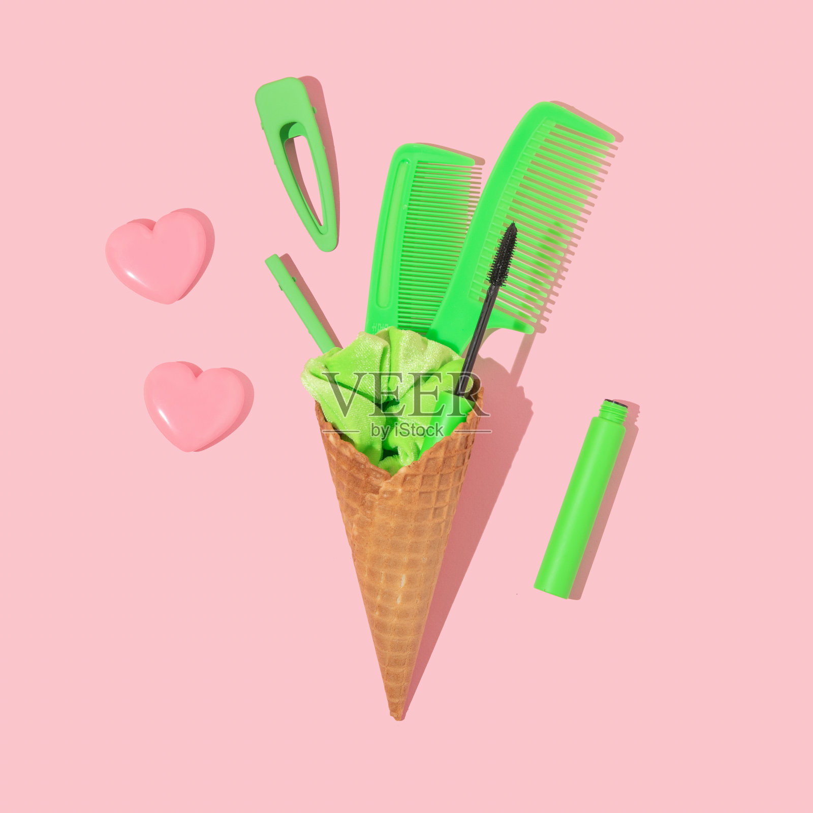 夏天的创意布局与冰淇淋蛋筒和霓虹绿色发圈，发卡，梳子和睫毛膏在粉彩粉色的背景。八九十年代复古时尚美学发廊理念。最小的夏季理发师的想法。照片摄影图片