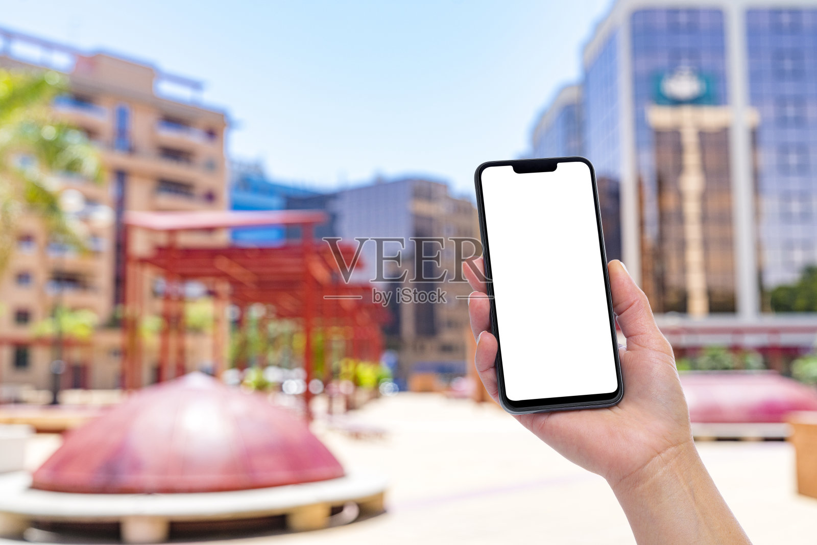 手持黑屏智能手机和办公大楼背景照片摄影图片