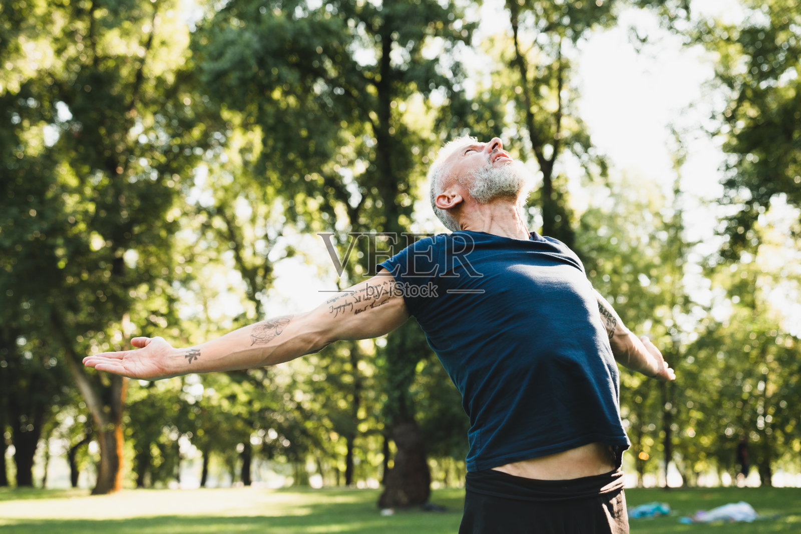 特写镜头的自由和快乐。穿着运动服的健康成熟男子在公园森林的户外瑜伽课上做呼吸练习。照片摄影图片