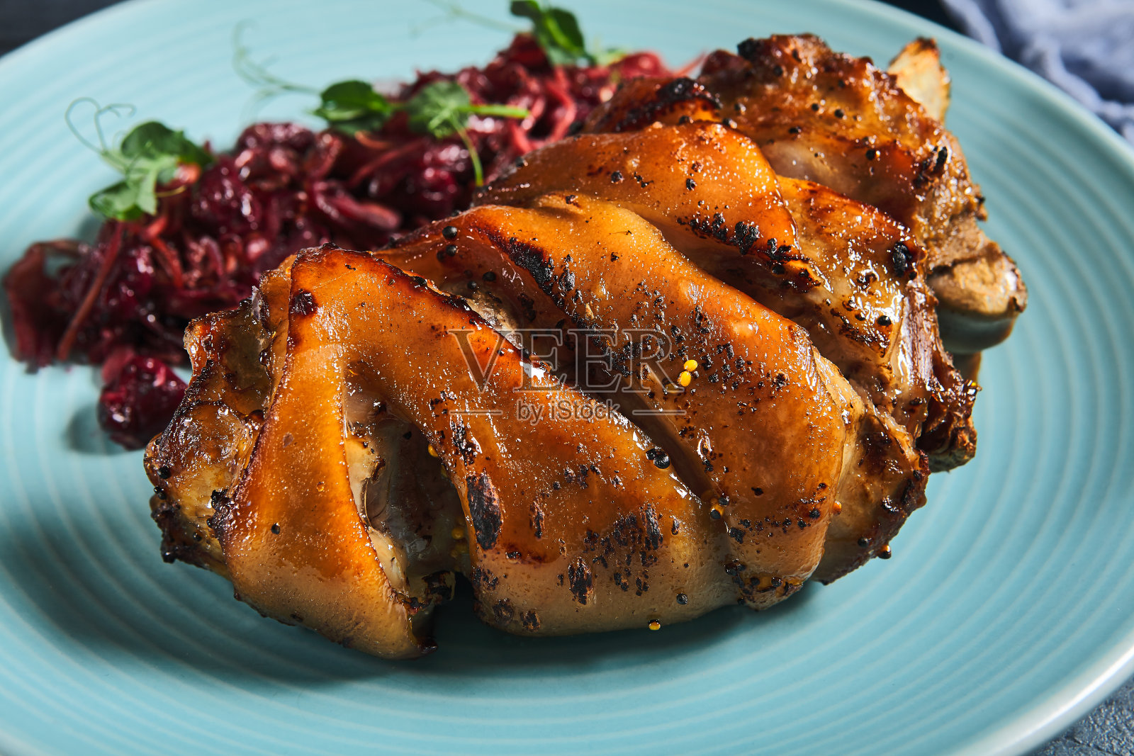 德国传统菜肴schweinshaxe。蓝色盘子里的烤火腿和酸菜。石底卷心菜烤猪肘。餐厅肉类菜单。照片摄影图片