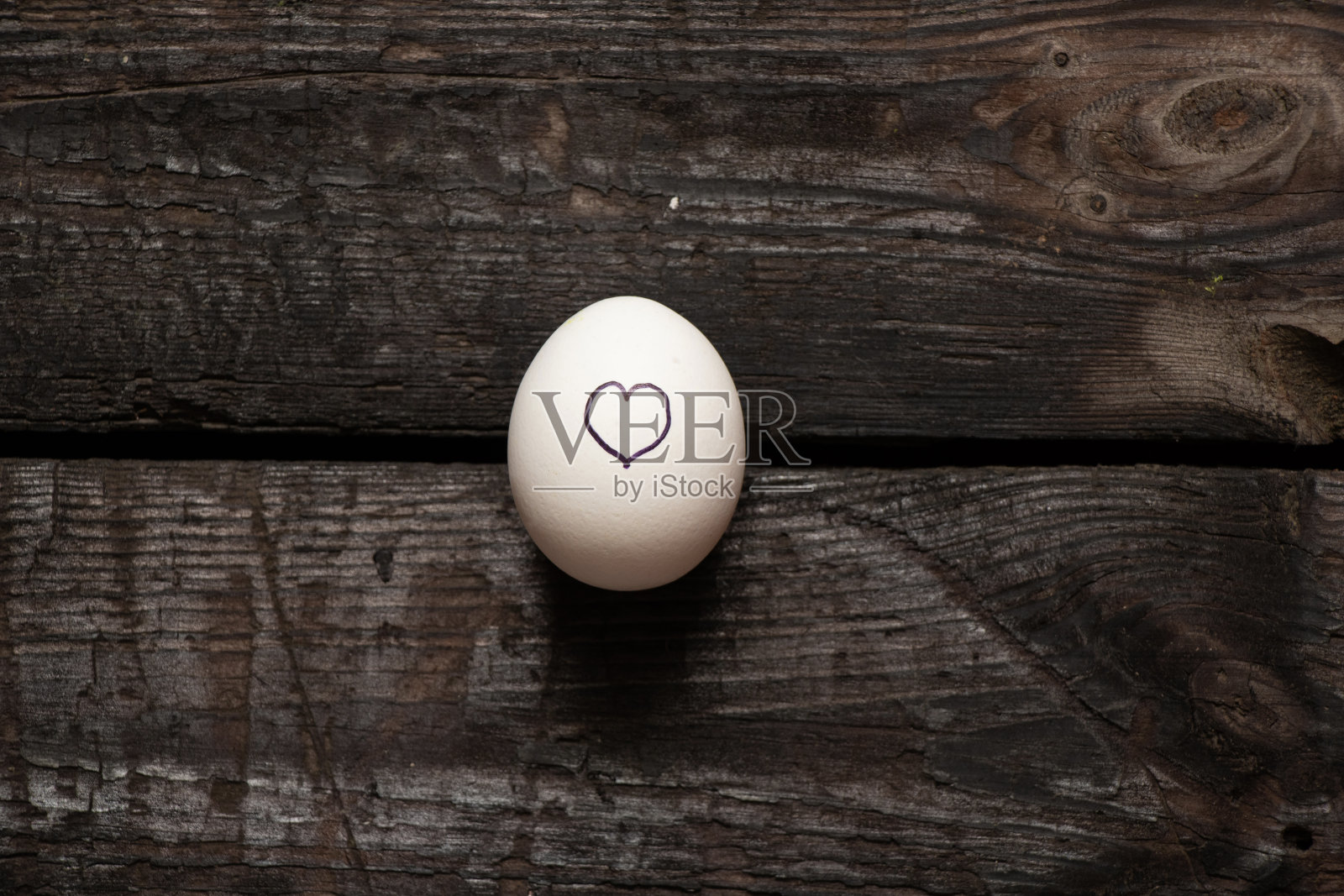 旧木桌上一只鸡蛋上画着心，爱照片摄影图片