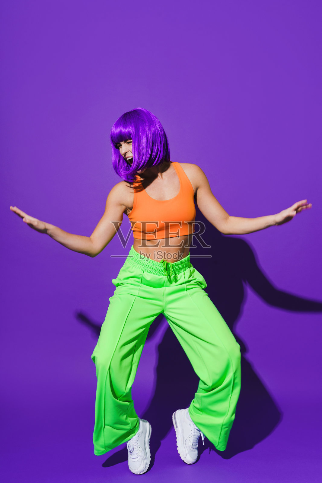 无忧无虑的女子舞者穿着五颜六色的运动服在紫色的背景下玩耍照片摄影图片