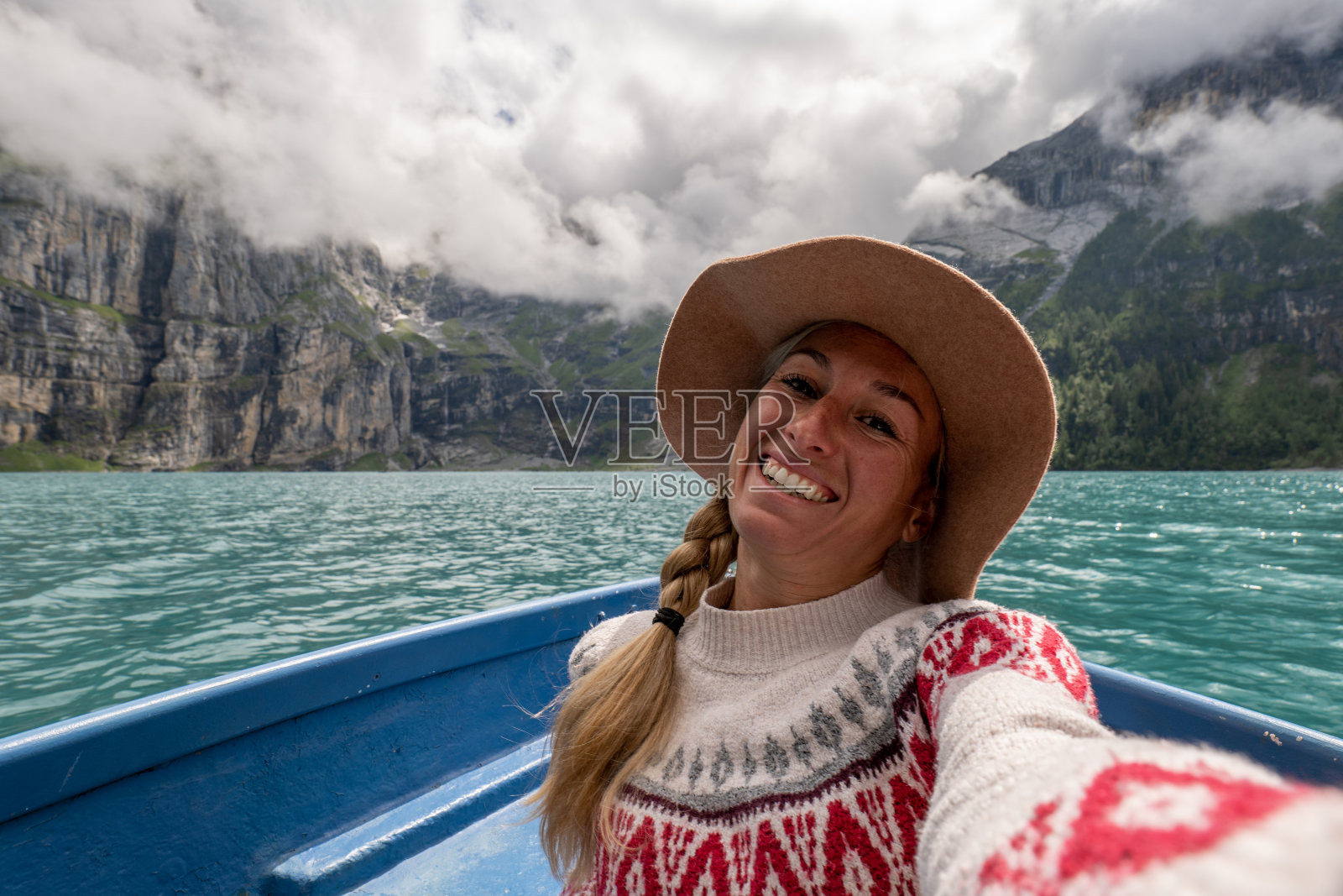 年轻女子在瑞士阿尔卑斯山高山湖泊的划艇上自拍，户外旅行乐趣照片摄影图片