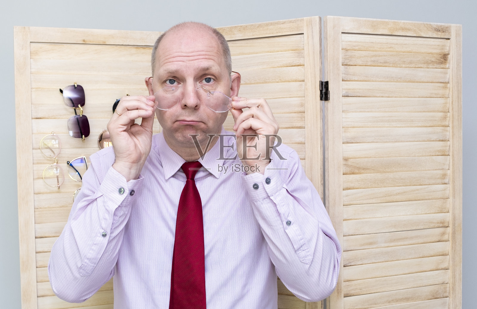 穿着衬衫系领带的50岁白人男子打碎了眼镜，很生气。挑出眼镜。照片摄影图片