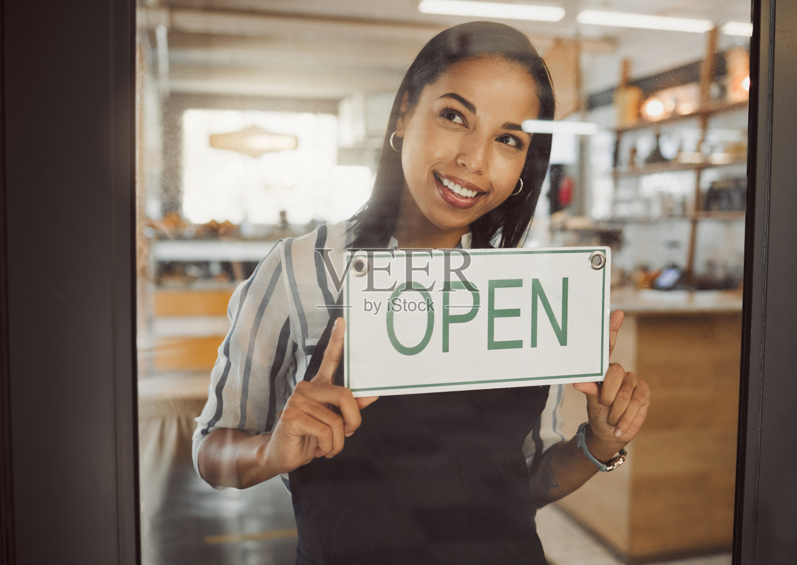 女店主在店铺门口悬挂“营业中”标牌，迎接顾客。咖啡馆已准备就绪，开始营业照片摄影图片