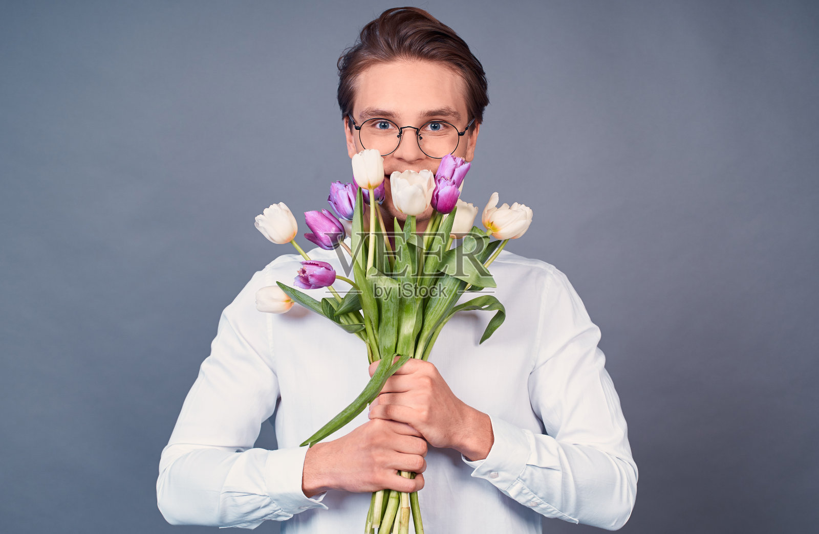 手持白色和粉色郁金香花束的年轻男人照片摄影图片