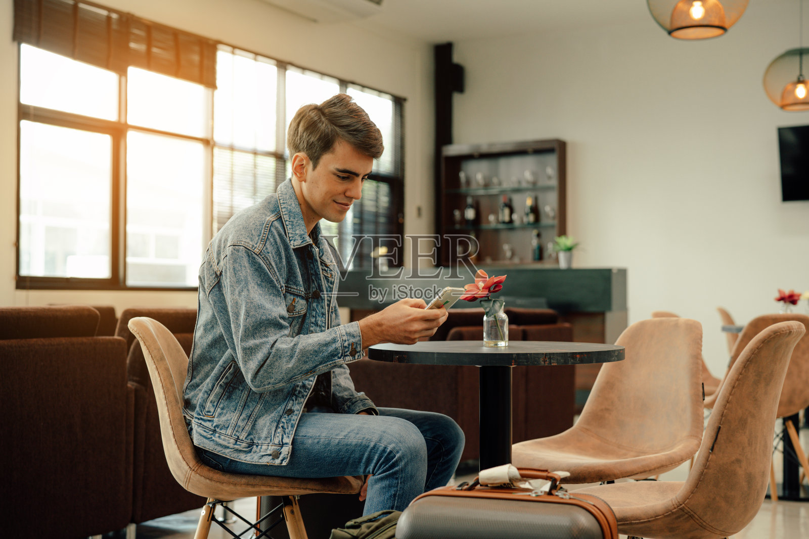 青年旅客拿着手机看。照片摄影图片