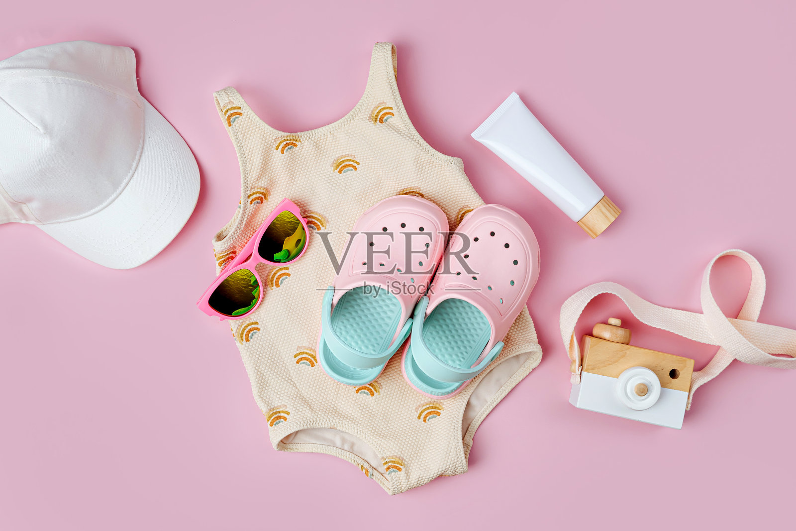 时尚泳装，太阳镜，沙滩拖鞋和儿童防晒霜。儿童沙滩配件的俯视图。暑假的概念。照片摄影图片
