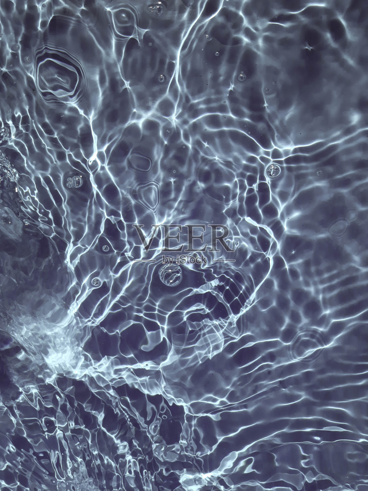 散焦模糊透明蓝色，清澈平静的水面纹理与飞溅和气泡。时髦的抽象自然背景。水在阳光下起伏。照片摄影图片