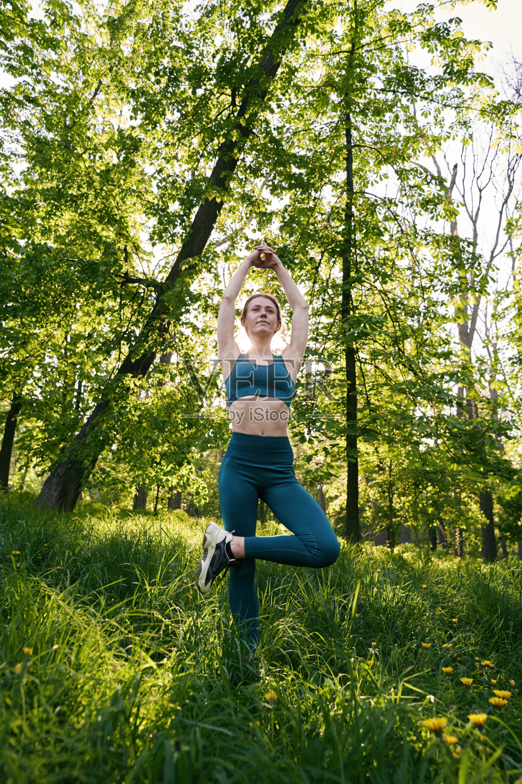 平静的女人在绿色的树林里做瑜伽照片摄影图片