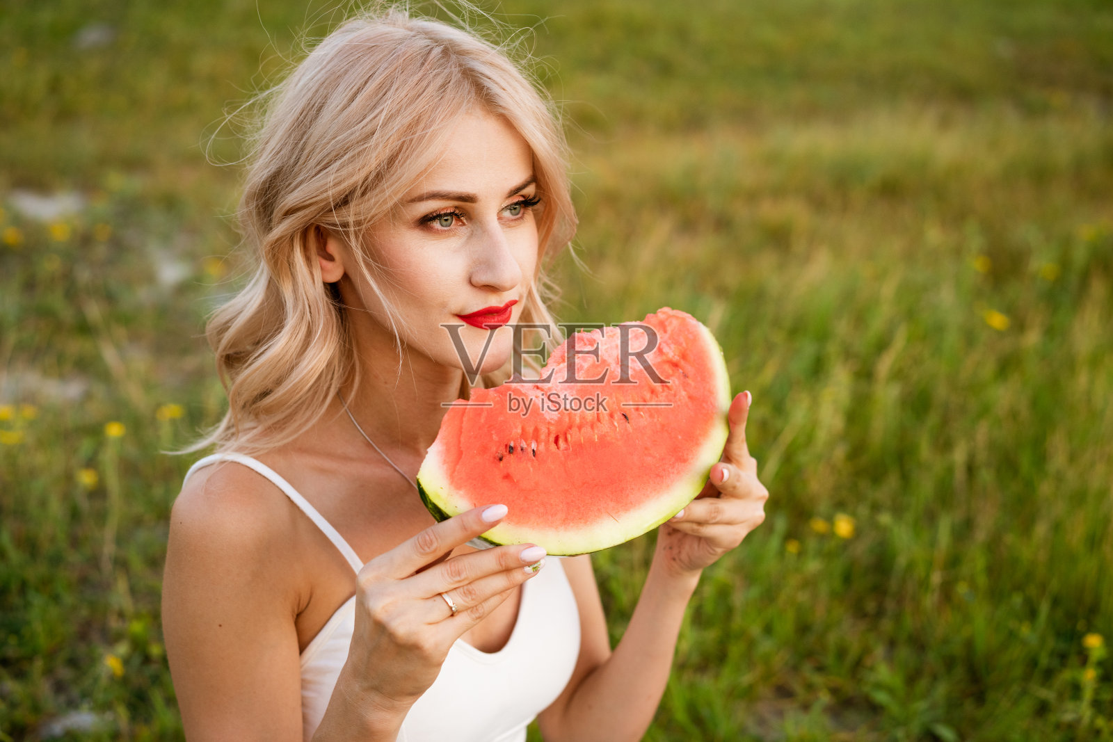 一个女人在大自然中咬西瓜的特写肖像。照片摄影图片