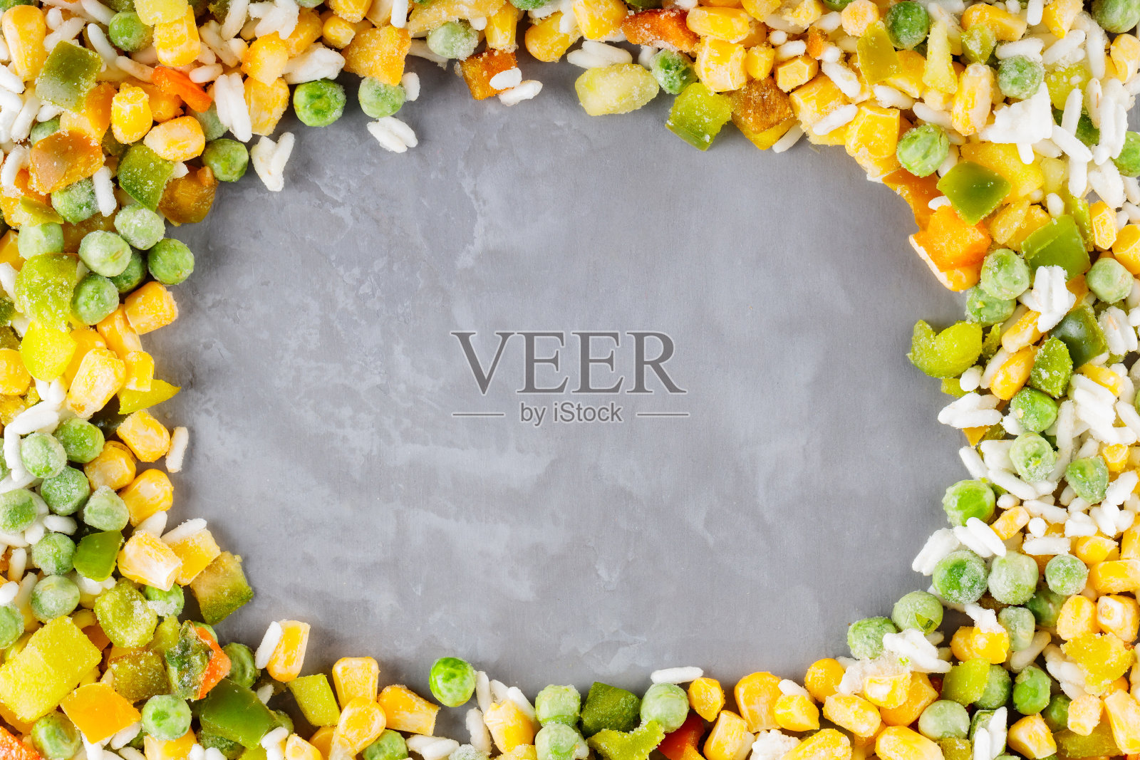 在灰色的背景上混合了冷冻蔬菜和大米。冷冻蔬菜保留所有的营养:青豆，玉米，甜椒。健康冷冻食品概念。前视图。本空间照片摄影图片